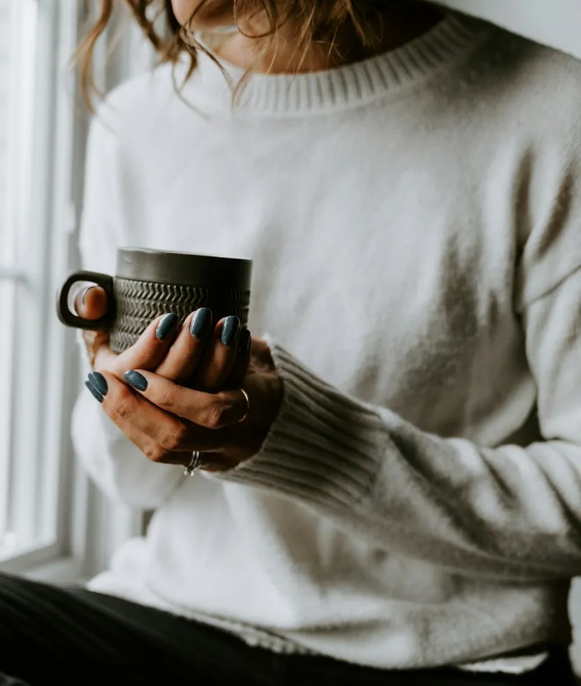 Creator met een kop koffie bij het raam, aan het begin van de werkdag